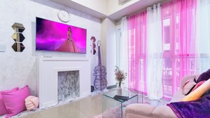 A modern living room with a flat-screen TV, a fireplace, a glass coffee table, and a sofa.