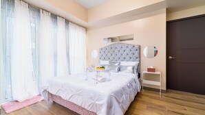 A bedroom with a large bed, a bedside table, a mirror, and a door.