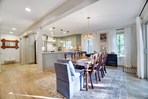 Una cocina amplia con zona de comedor, que cuenta con una gran mesa de madera y sillas, una isla integrada y luminarias colgantes.