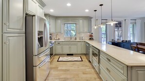 A modern kitchen with white cabinetry, stainless steel appliances, and pendant lighting.