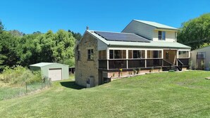 A two-story house with a covered porch and solar panels on the roof. - Yellowstone | quiet country farmhouse | fast internet (Rydal)