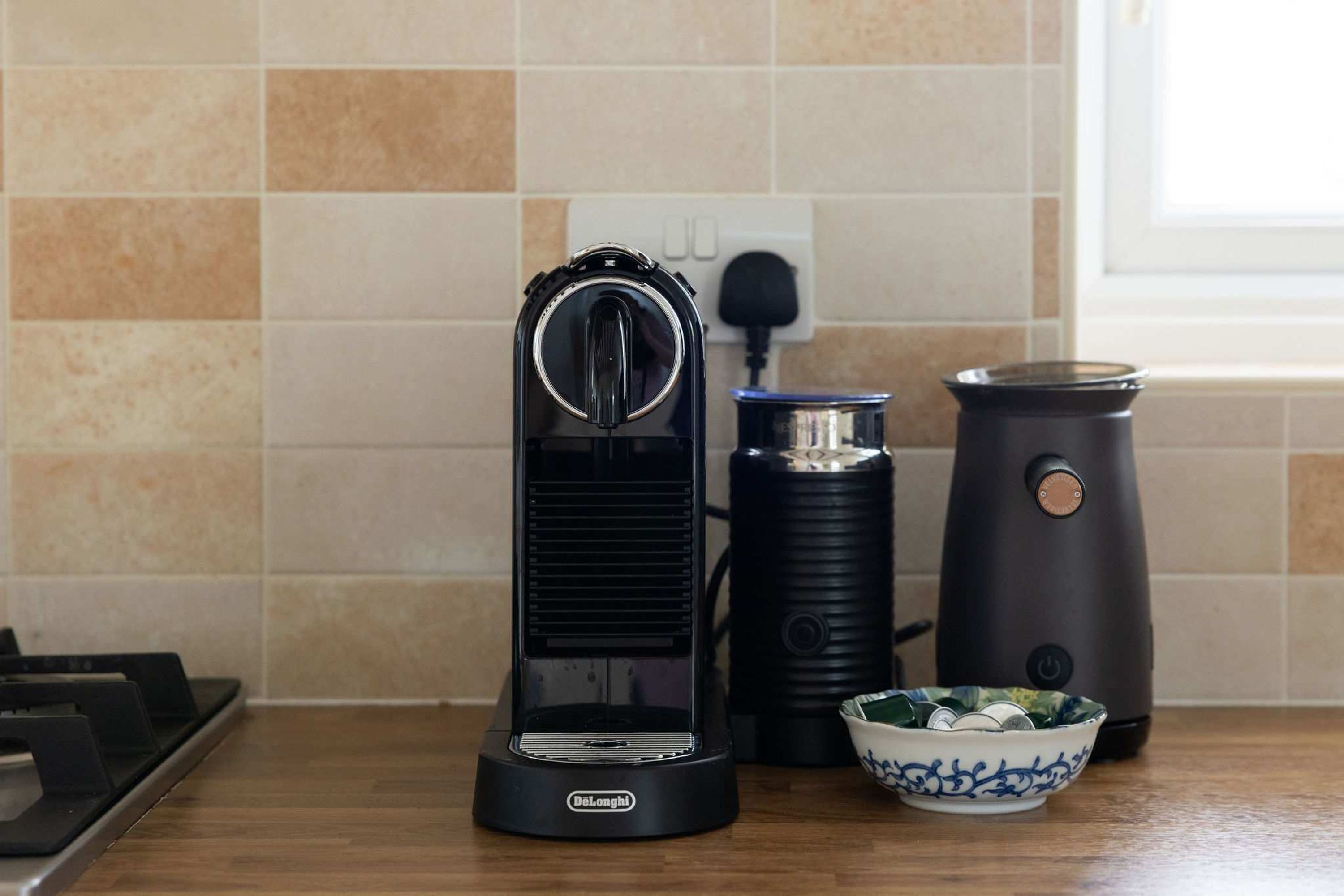 A kitchen with a coffee maker, a kettle, and a bowl on the counter.
