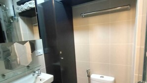 A bathroom with a white sink, a toilet, and a glass shower enclosure. - Condo with Water Views (Pasay City)