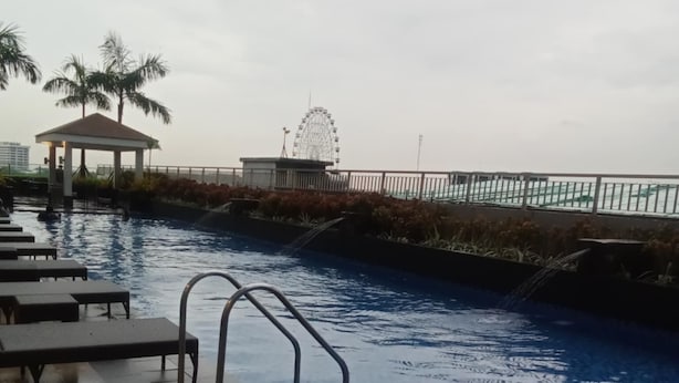 A swimming pool with lounge chairs and a gazebo. - Condo with Water Views (Pasay City)