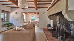 Un accogliente soggiorno con divano, camino e attrezzi d'epoca, con vista su una sala da pranzo.
