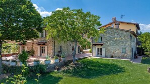 Una casa de piedra con jardín y zona de estar al aire libre.