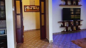 Un salon doté d’une porte coulissante de style japonais traditionnel, d’un téléviseur posé sur un meuble en bois et d’un sol à motifs.