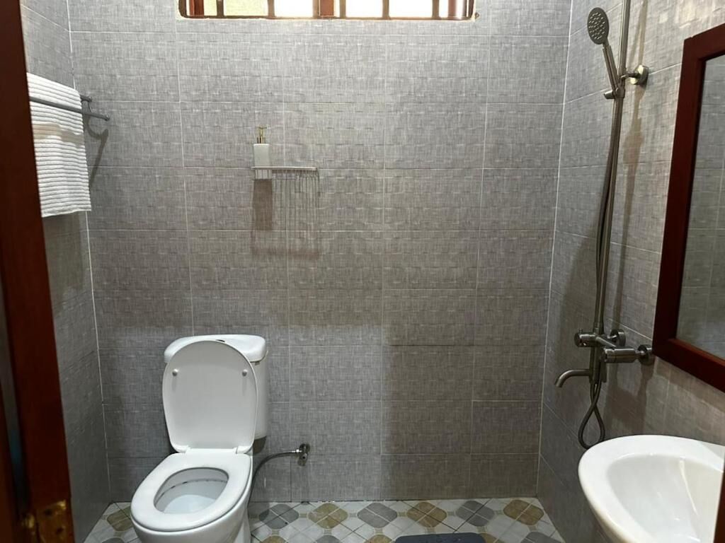A small bathroom with a toilet, a shower, and a sink.