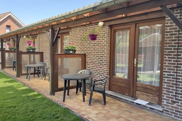 A patio area with a brick wall, a wooden pergola, and outdoor furniture.