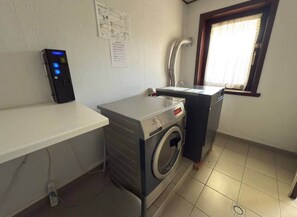 Un espace buanderie comprenant un lave-linge, un sèche-linge, un évier et un panneau de commande.