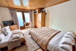 Ein Schlafzimmer mit einem Bett, einem Fernseher, einem Kleiderschrank und einem Sessel.