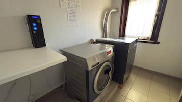 Een wasruimte met een wasmachine, een droger, een wasbak en een bedieningspaneel.