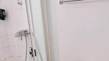 Une salle de bain avec une douche à parois de verre, des toilettes blanches et une barre d’appui.