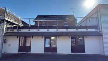 Un bâtiment à deux étages, doté d’un toit plat, d’une entrée abritée et d’un espace extérieur clôturé.