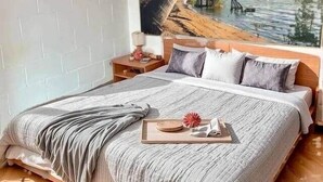 A bedroom with a large bed, a nightstand, a painting of a beach scene, and a wooden ceiling. - Résidence Rachel 16 - Shape - Mons (Mons)