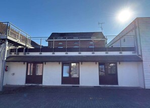 A two-story building with a flat roof, a covered entrance, and a fenced outdoor area. - Résidence Rachel 13 - Shape - Mons (Mons)