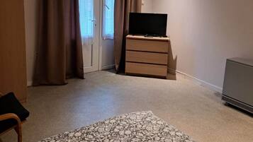 Une pièce comprenant un lit, une commode, un téléviseur et une porte avec des rideaux.