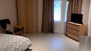Een slaapkamer met een bed, bureau, stoel, kast en een televisie.