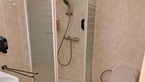 Een badkamer met een douche met glazen wand, een toilet, een wastafel en een handdoekhouder.