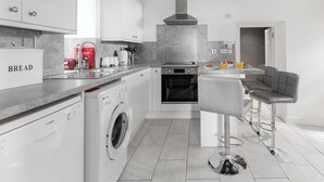 Una cucina moderna con lavatrice Bosch, forno integrato e zona pranzo con sgabelli da bar.