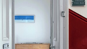 Un passadís amb sòl de fusta, paret vermella i un cartell que diu "Above the Bay".