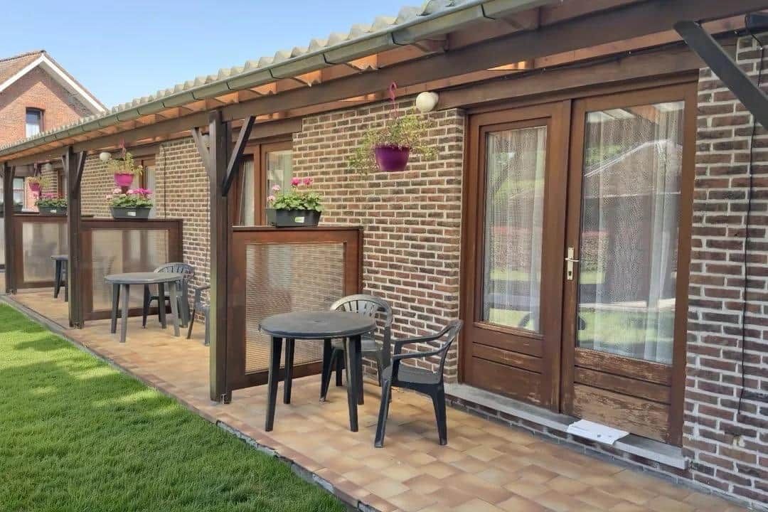 Un espace patio agrémenté d’un mur en briques, d’une pergola en bois et de mobilier d’extérieur.