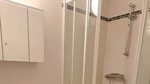 A bathroom with a glass-enclosed shower, a sink, and a cabinet.