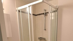 Un bagno moderno con doccia vetro, water e lavabo con mobiletto.