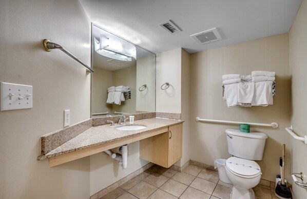 Une salle de bain équipée d’un lavabo, de toilettes et de barres d’appui.