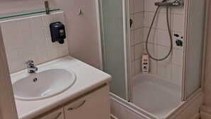 A bathroom with a sink, mirror, glass shower enclosure, and a handheld showerhead. - Résidence Rachel 03 - Shape - Mons (Mons)