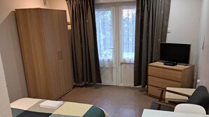 A hotel room with a bed, a desk, a television, a wardrobe, and a window with curtains. - Résidence Rachel 03 - Shape - Mons (Mons)