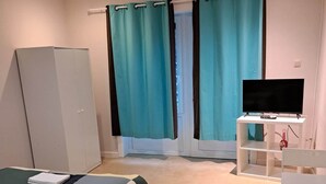 A bedroom with a bed, a desk, a television, and curtains. - Résidence Rachel 03 - Shape - Mons (Mons)