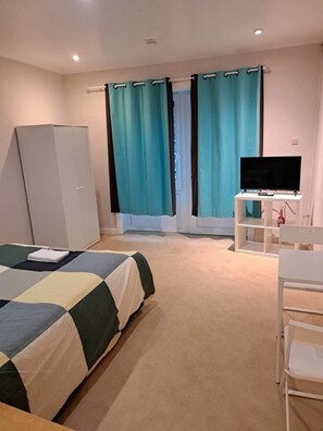 Una camera da letto con un letto, una scrivania, una televisione e tende.