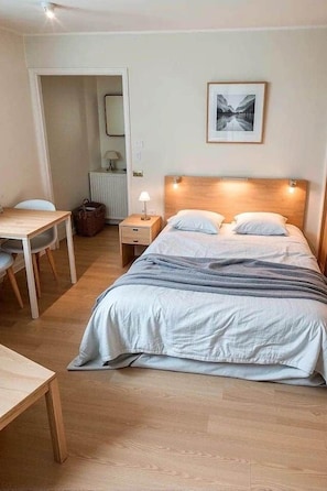 A bedroom with a bed, bedside table, lamp, and a framed picture on the wall.