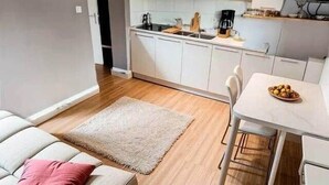 Een moderne keuken met witte kasten, een eettafel en een bank met een roze kussen.