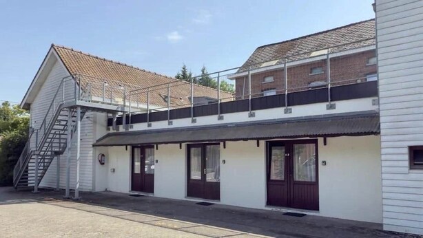 Un bâtiment à deux étages doté d’un porche avant couvert, d’un escalier menant à l’étage supérieur et d’une borne d’incendie au rez-de-chaussée.