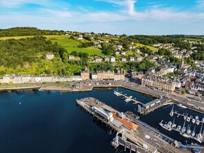 A coastal town with a marina, residential buildings, and a hilltop view.