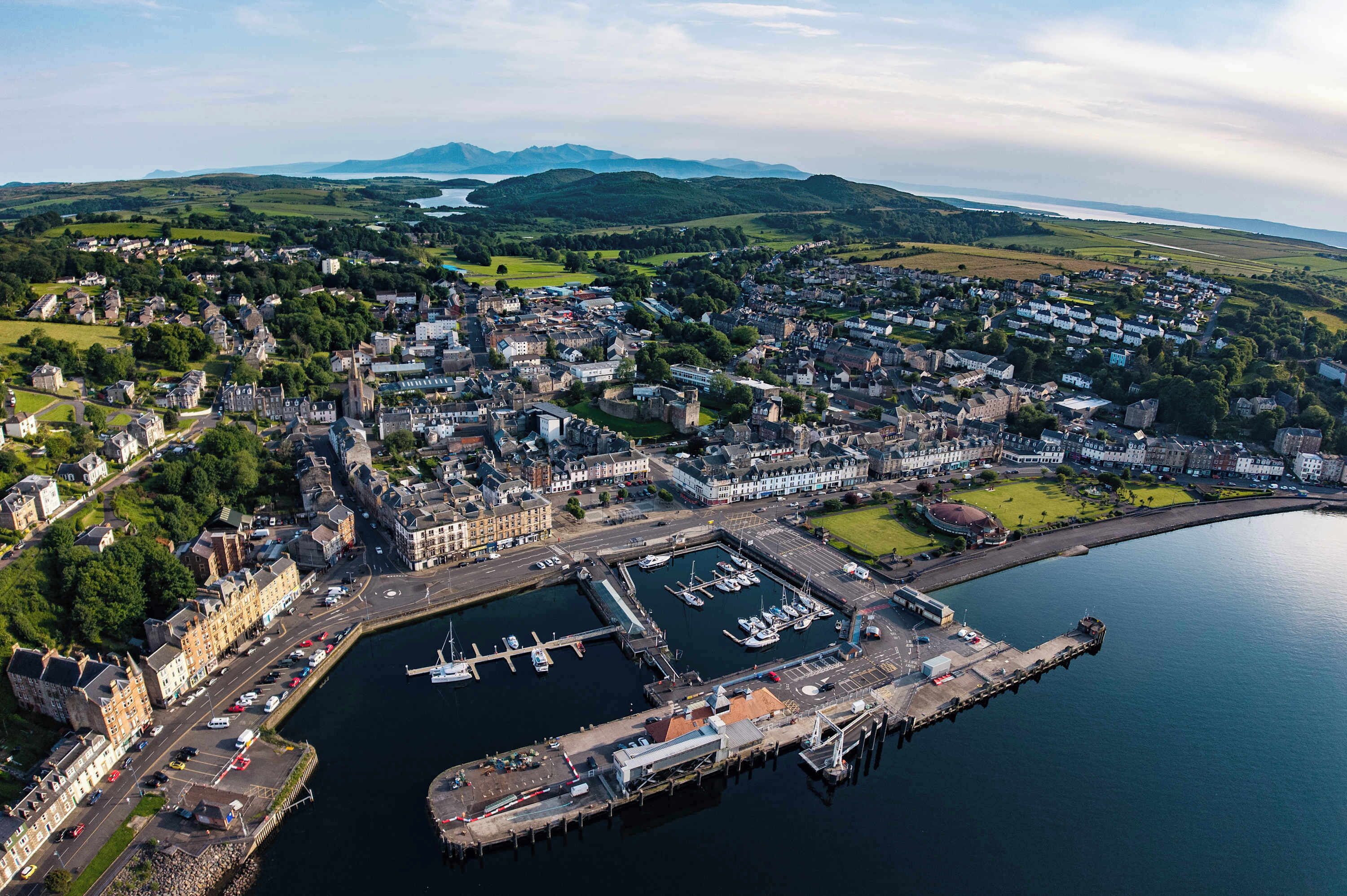 Vue aérienne d’une ville côtière avec un port de plaisance, des bâtiments historiques et un port.