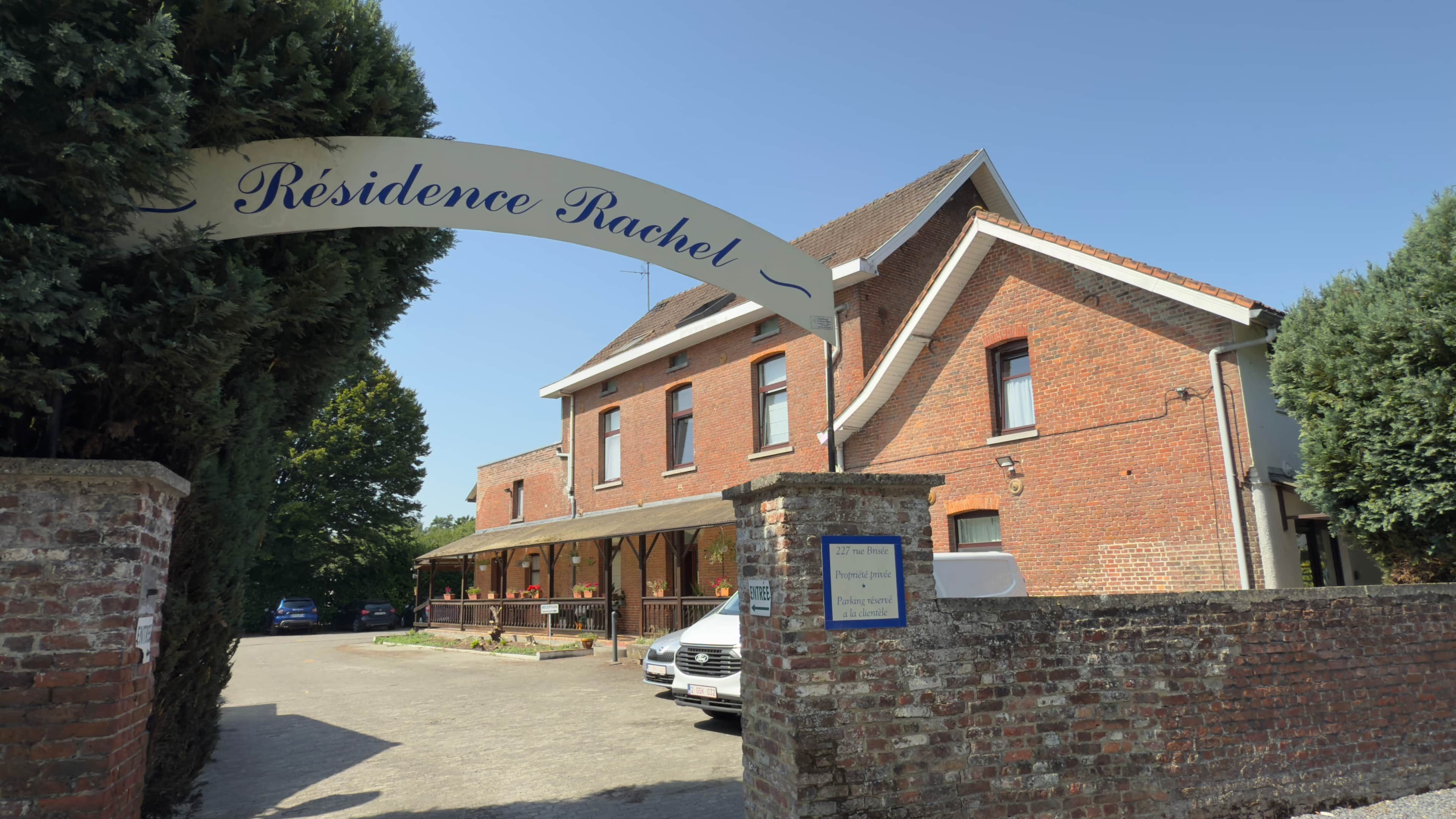 A brick building with a sign reading 'Résidence Rachel' and a covered entrance area.