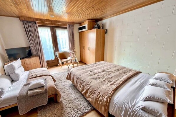 Une chambre à coucher avec un lit, une télévision, une armoire et une chaise.