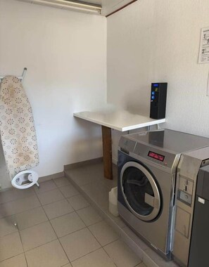 Un espace buanderie comprenant un lave-linge, un sèche-linge et une petite étagère.