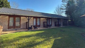 A brick building with a tiled roof, a covered patio, and a grassy yard. - Résidence Rachel 25 - Shape - Mons (Mons)