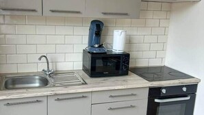 A compact kitchen with a sink, a microwave, a stovetop, and a built-in oven.