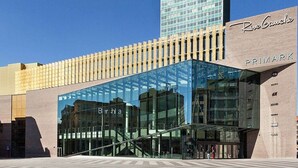 A modern building with a glass facade, a prominent sign for 'Riv Gauche,' and a visible entrance.