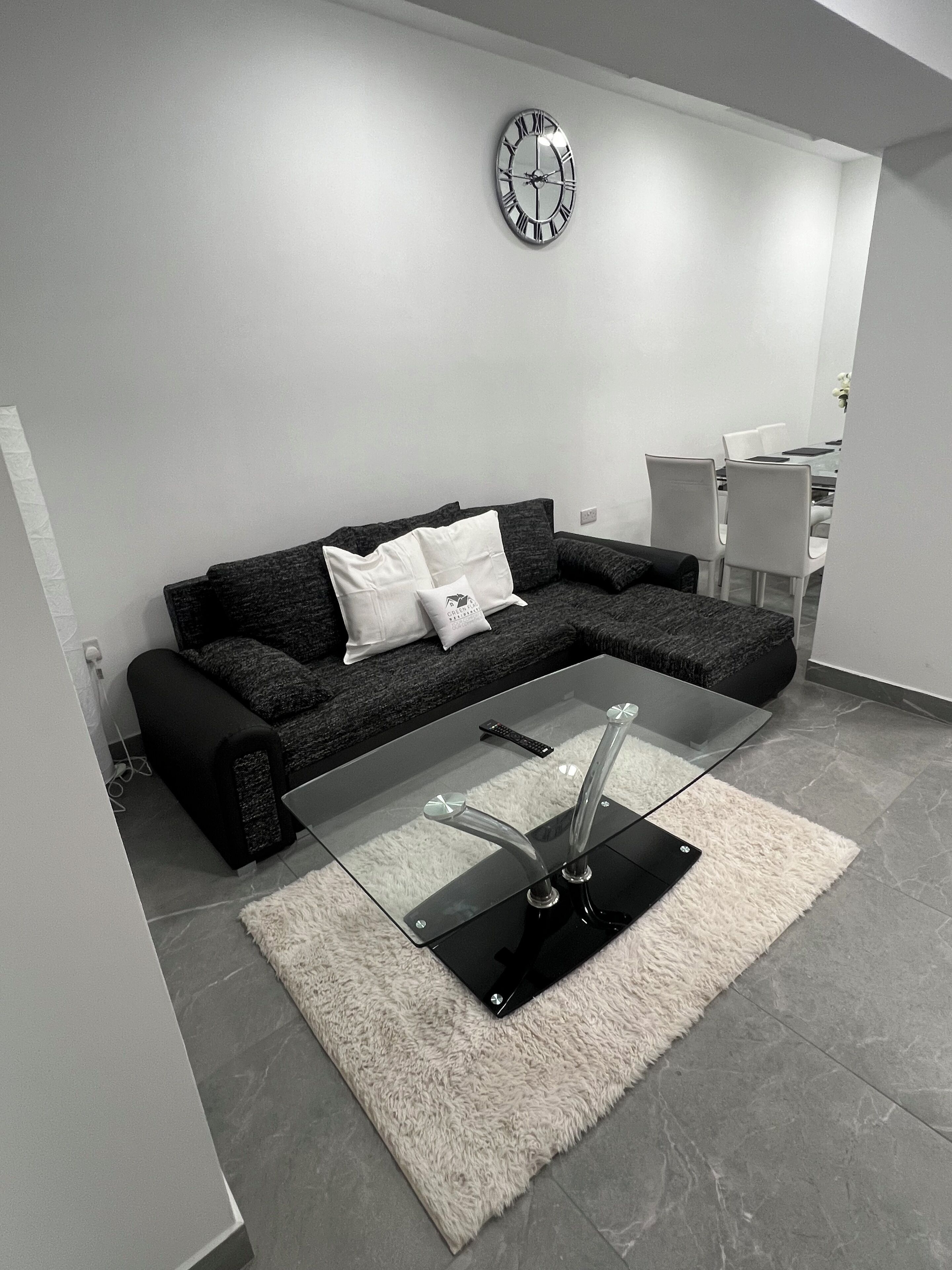 Una sala moderna con un sofá modular, una mesa de centro de vidrio y un reloj en la pared.