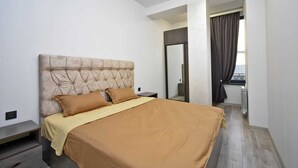A bedroom with a tufted headboard, a bed with brown bedding, a nightstand, a mirror, and a view of a balcony with curtains. - 2-bedroom apartment in fantastic Yerevan with WiFi, AC (Yerevan)