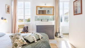 Un dormitorio con cama, ventana, baño con lavabo y espejo.