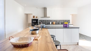 Una cocina moderna con encimera de madera, estufa empotrada y una isla grande con una caja morada etiquetada 'Cuisinart 7B'.