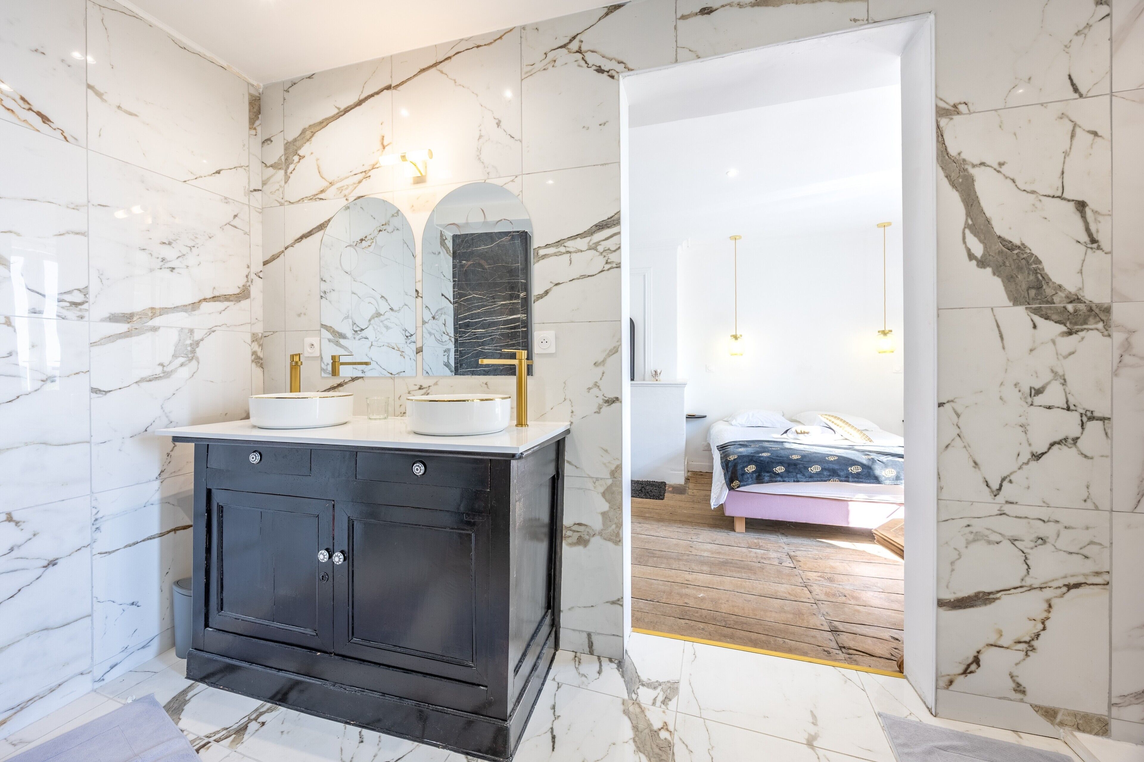 A bathroom with marble walls, a black vanity, and a mirror.