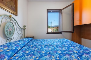 Un dormitorio con una cama, una ventana y vistas a edificios.